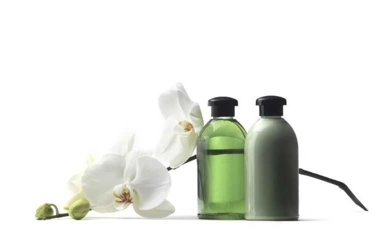 Zwei Flaschen mit grüner Flüssigkeit neben einer weißen Orchidee.