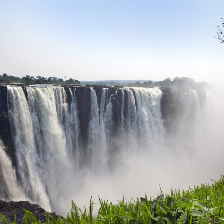 Ein beeindruckender Wasserfall, umgeben von üppigem Grün und leichtem Nebel.